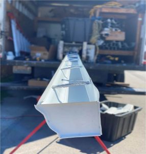 Close-up picture of a gutter coming out of a cutting machine in the back of a truck.