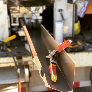 Picture of a gutter and red scissors for metal.