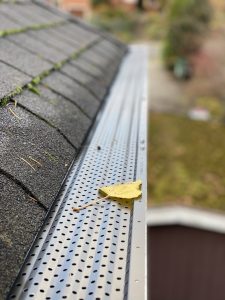 Picture of a new gutter guard with a yellow leaf on it.